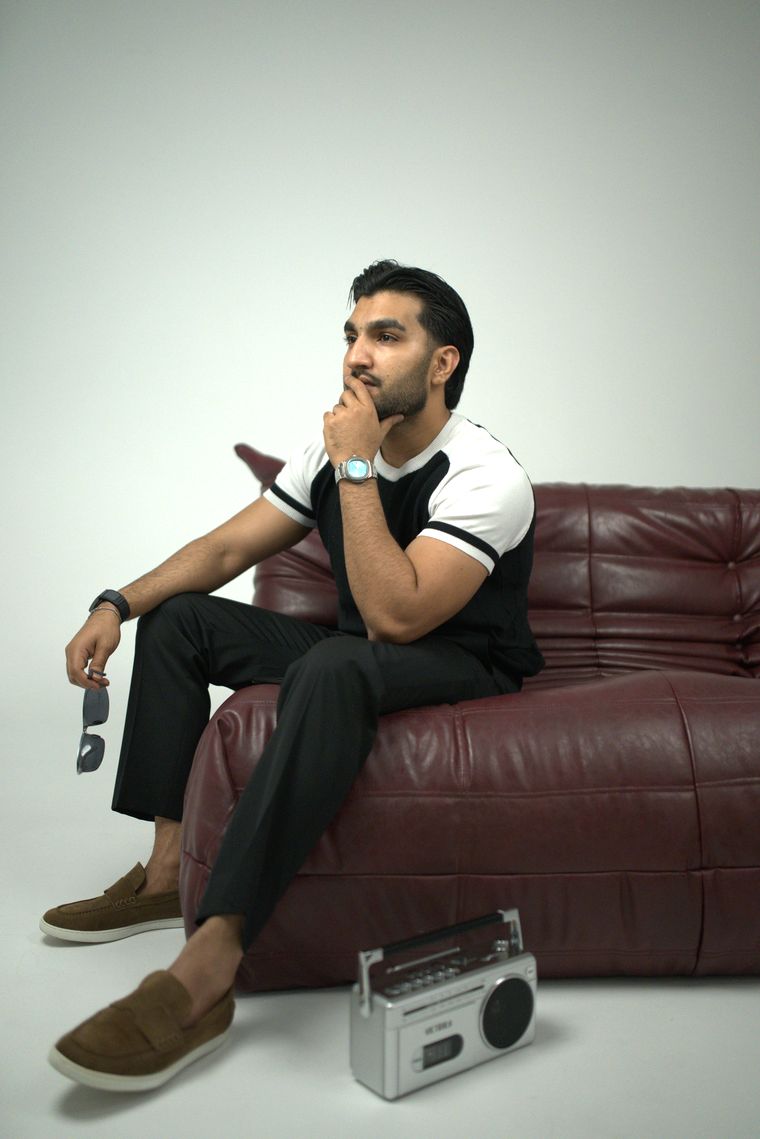 Sultan Bhatti seated thoughtfully on a burgundy sofa