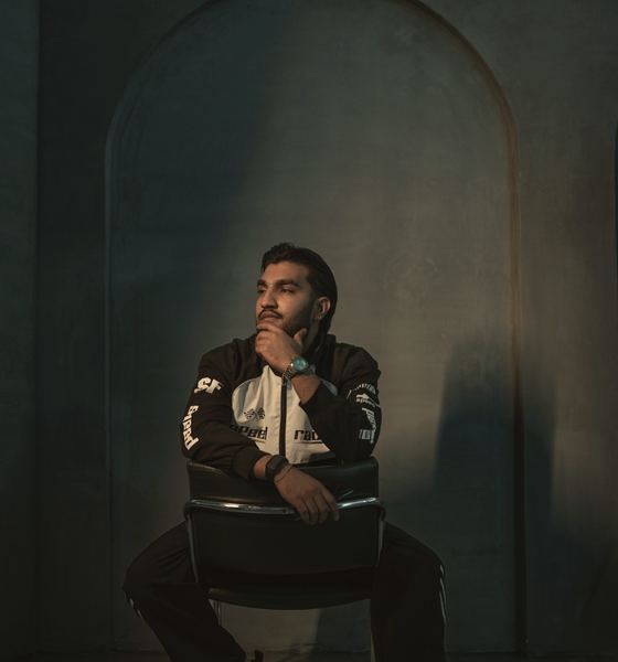 Sultan Bhatti in a racing jacket in a dark arched studio