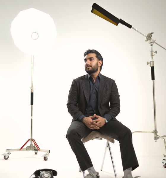 Sultan Bhatti working on a laptop on a burgundy sofa